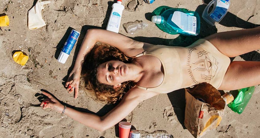 donna stesa su una spiaggia sporca di plastica